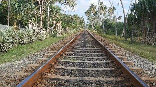 Camera move forward along the railway with exotic tropical nature at background. The rail tracks close up. Point of view of train moving along tracks in asia. Slow motion Close up