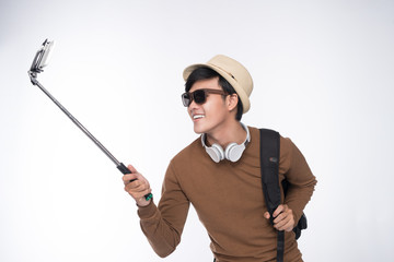 Young tourist asian man taking selfie picture over grey background