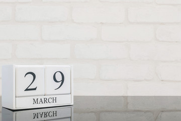 Closeup white wooden calendar with black 29 march word on black glass table and white brick wall textured background with copy space , selective focus at the calendar