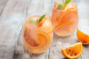 Cold refreshing drink with blood orange slices in a glass on a wooden background. Selective focus, copy space.