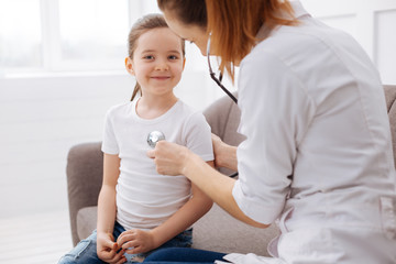 Fototapeta premium Cute delighted girl paying annual visit to her doctor