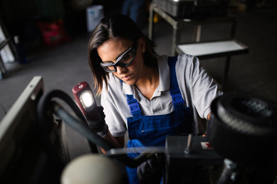 female mechanic looking for a fault on a compressor engine using a flashlight