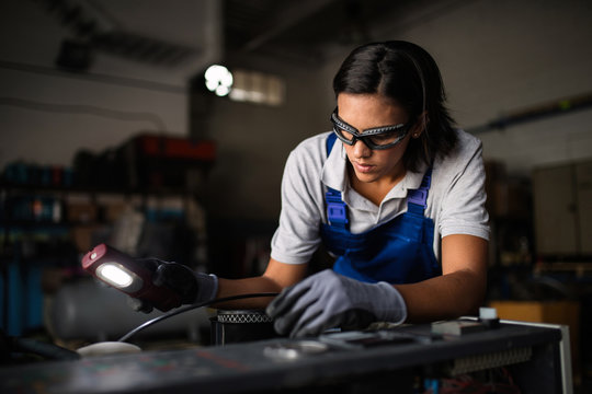 female mechanic looking for a fault on a compressor engine using a flashlight