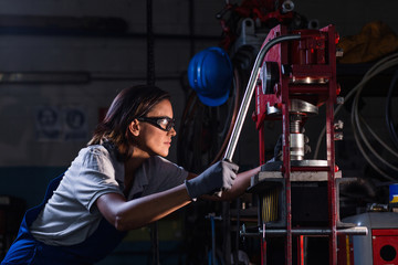 female mechanic operating hydraulic press