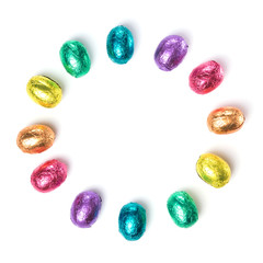 Circle made of chocolate easter eggs wrapped in multi colored foil isolated on white background