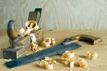 carpentry tools concept, vintage equipment for working with wood. planer and saw on wooden table with shavings