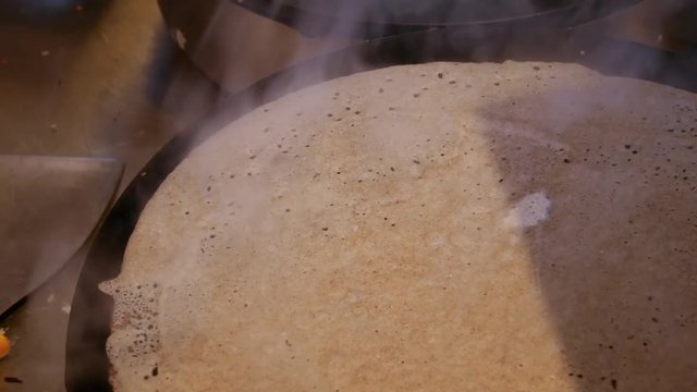 4K close up of a buckwheat crepe getting brown. A crepe, or buckwheat pancake, in his cr&ecirc;perie restaurant, in Brittany. Galette bretonne, creperie, Rennes, Bretagne, France. traditional food specialty
