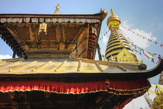 Low angle view temple roof with top of Stupa Swayambhunath with prayer flags, Kathmandu Valley, Nepal