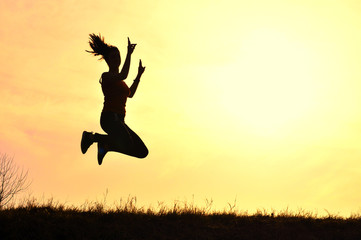 Young woman jumping high in happiness  at sunrise. Happy teenage girl jump in sunset 