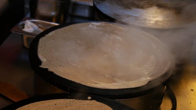 4K close up of a man pouring crepe batter a crepe, or buckwheat pancake, in his cr&ecirc;perie restaurant, in Brittany. French traditional food.  Galette bretonne, creperie, Rennes, Bretagne, France.
