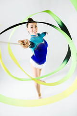 Beautiful gymnast athlete doing exercise with ribbon. Isolated on white.