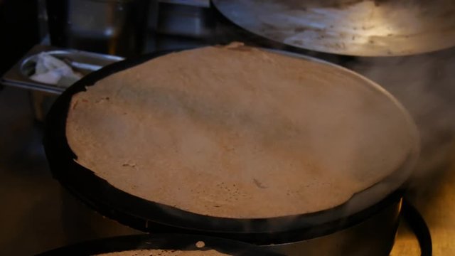 4K close up of a crepe cooking and heating, or buckwheat pancake, in Brittany. French traditional food specialty.  Galette bretonne, cr&ecirc;perie, Rennes, Bretagne, France.