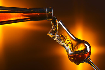 Pouring alcohol into a glass on dark background