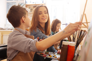 Charming young artist helping children in the art studio