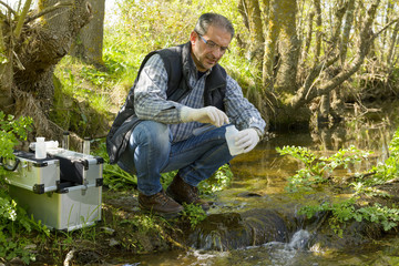 View of a Biologist take a sample in a river. - obrazy, fototapety, plakaty
