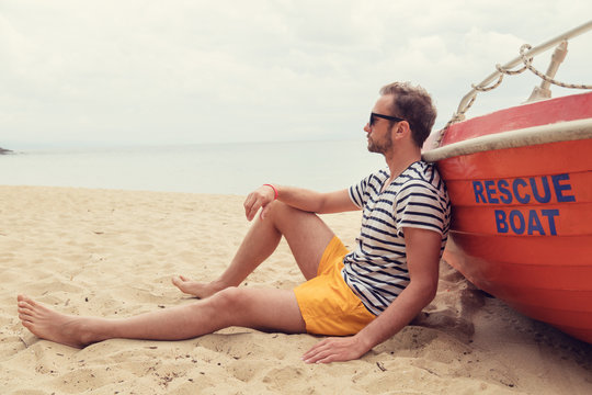Lifeguard posing with his boat on the beach.
