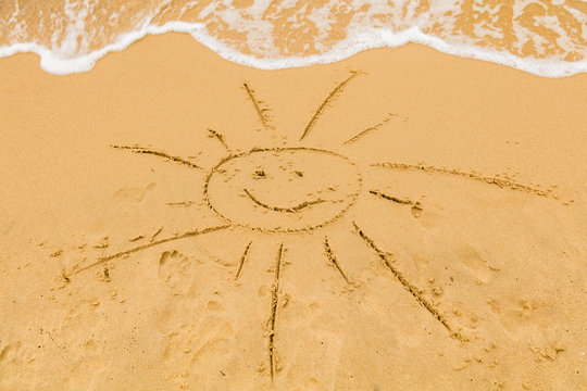 Sun drawing in the sand of ocean / sea beach.