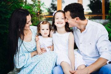 Father hugs his daughters sitting with their mother outside