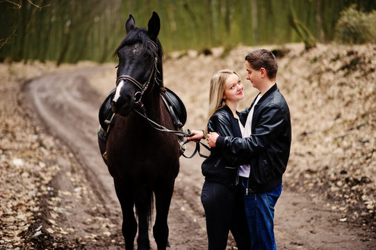 Young stylish couple in love near horse at autumn forest.