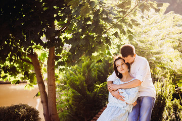 Naklejka premium Woman in long blue dress lies in man's arms while they rest on wooden bench