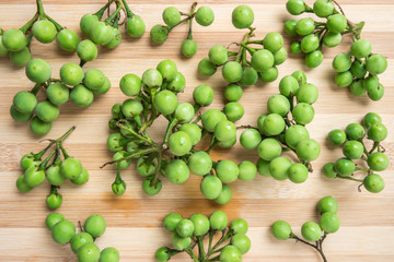 solanum torvum or pea eggplant bunch on bamboo wooden table. Top view.