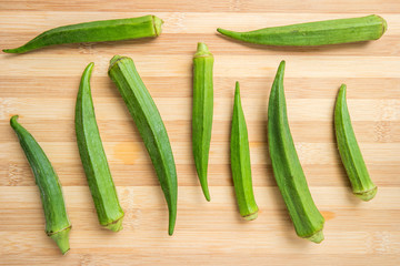 fresh okra on bamboo wooden table. Top view.