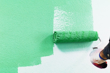 rasit hand wall paint using a paint roller while working indoors
