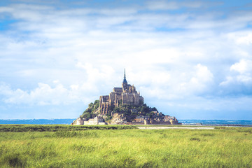Panoramic view of famous Le Mont Saint-Michel Abbey on a sunny day with blue sky and clouds, Normandy, France