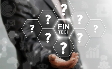 Finance technology FAQ Business concept. Businessman offers FINTECH icon on virtual screen on background of questions. Financial question and answer