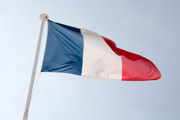 The French flag against blue cloudy sky.
