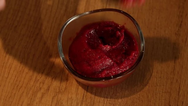 4K close-up of the hand of a man dipping a spoon in a red scoop ice-cream, blackcurrant, strawberry and raspberry flavor. 