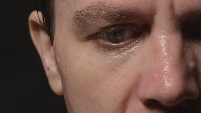 Sweating face on young adult man, who wiped it by hand- Close up