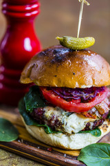 Tasty burger with beef with spinach and blue cheese served on a small board on a vintage background.