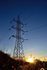 Fototapeta premium Electric tower backlit at sunrise, view from below