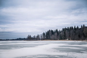 A peaceful winter landscape with a frozen lake in overcast day