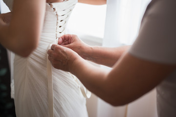 Obraz na płótnie Canvas Mother helping to wear wedding dress