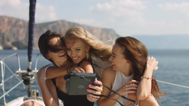 Three beautiful female friends make selfie on a yacht