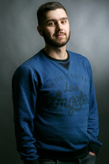Obraz premium Handsome bearded man with broad shoulders poses in blue sweater