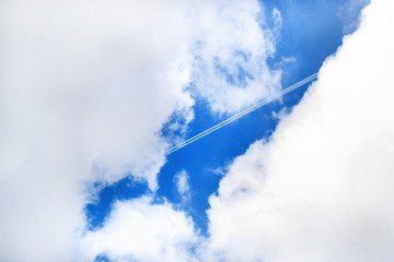 Airplane leaving trace on sky between clouds