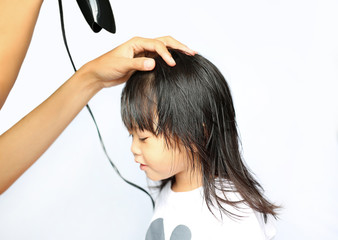 Mother drying hair of her child girl on white background