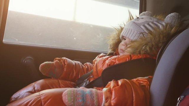 Dreaming pretty child in a car in the child safety seat in slow motion on sunny day. 1920x080