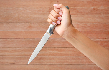 Hand holding a knife ready to strike down against plank wood
