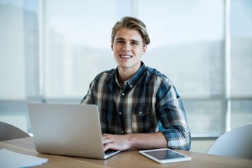 Smiling man working on laptop in office