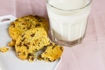 Chocolate chip cookies with milk on pink tablecloth