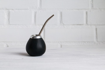 Traditional calabash gourd for mate tea drinking with straw on white table. Copy space.
