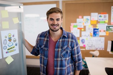 Fototapeta premium Smiling man standing near the wall with sticky notes
