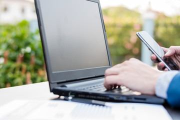 Handsome businessman wearing suit and using modern laptop outdoors and graph finance diagram.