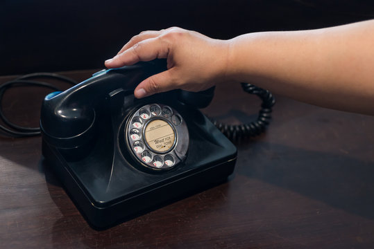 Catch the phone handle antique old black rotary telephone on the wooden table