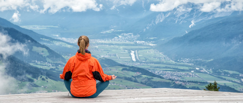 young woman meditate on top of the mountain
