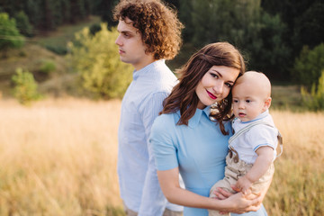 Young happy caucasian couple with little baby boy. Parents and son walking and having fun together. Mother and father playing with toddler outdoors. Family, parenthood, childhood, happiness concept.